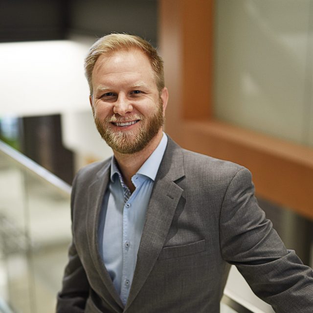 Portrait of Daniel standing inside a building against a stair railing